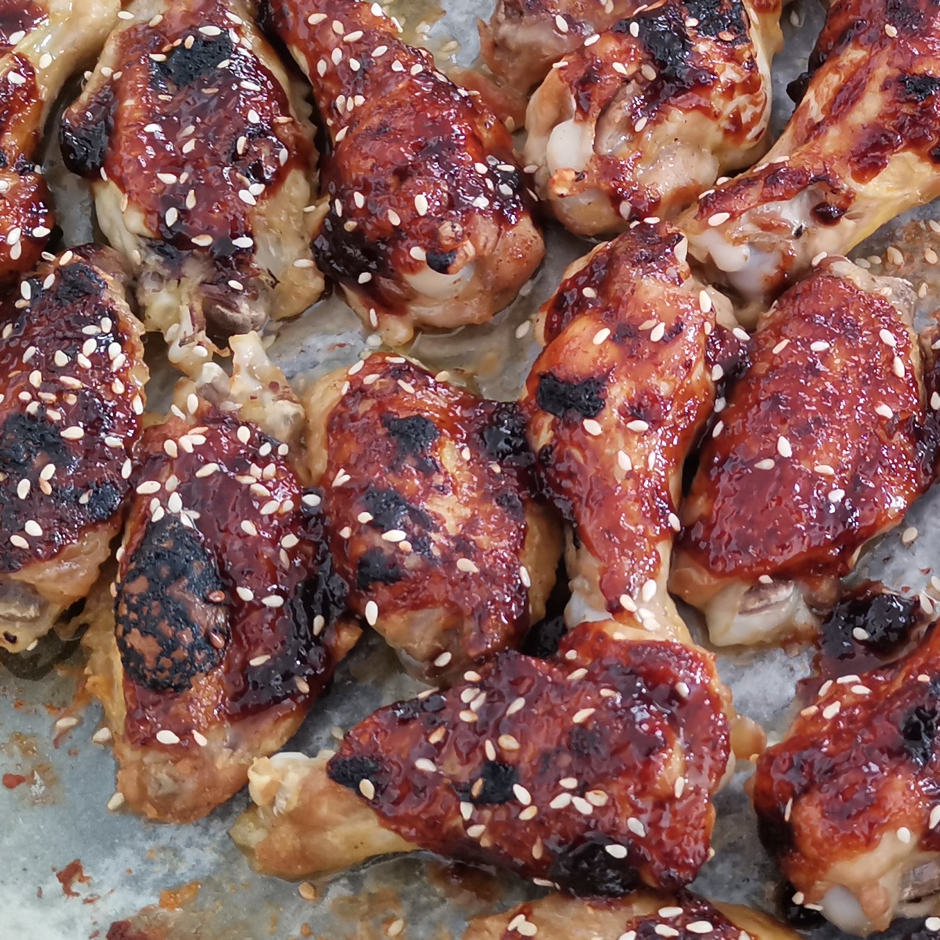 Slika perutničk, premazanih z lepljivo teriyaki omako in potreseno s praženim sezamom.